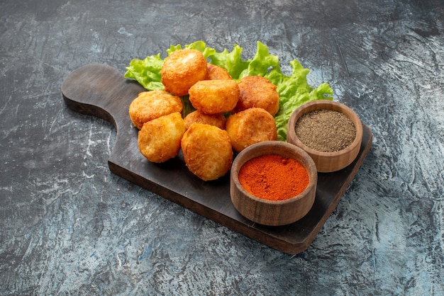 Bottom view fried cheese balls lettuce spice bowls on chopping board on table