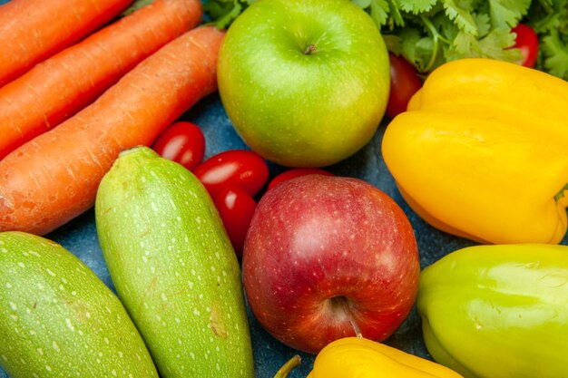 Bottom view fruits and vegetables bell peppers apples zucchini carrot coriander on blue table