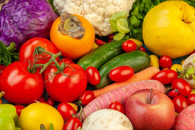 Bottom view fruits and vegetables radish cherry tomatoes persimmon tomatoes kiwi cucumber apples red cabbage parsley quince on blue table