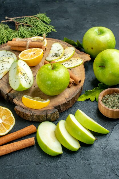 Bottom view green apples cinnamon sticks and lemon slices apple slices on wood board cut lemons apples on black table