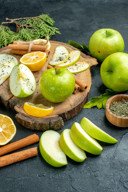 Вид снизу зеленые яблоки палочки корицы и дольки лимона дольки яблока на деревянной доске нарезанные лимоны яблоки на черном столе