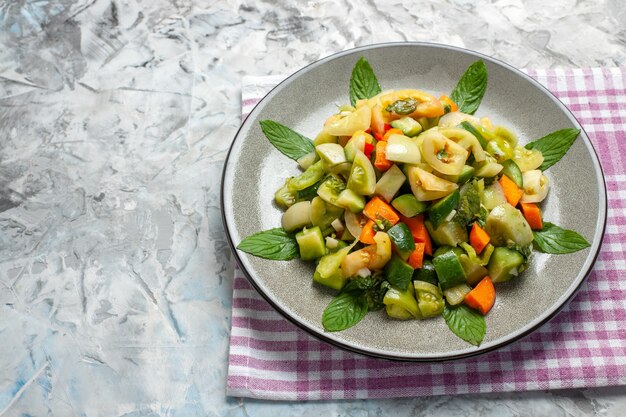 Bottom view green tomato salad on oval plate on dark