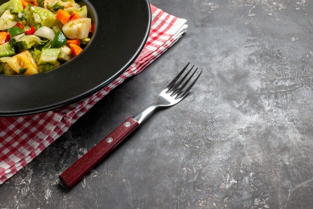 Bottom view green tomato salad on oval plate a fork on dark