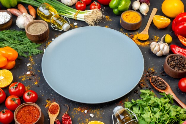 Вид снизу серое круглое блюдо со свежими овощами и другими продуктами на темном столе