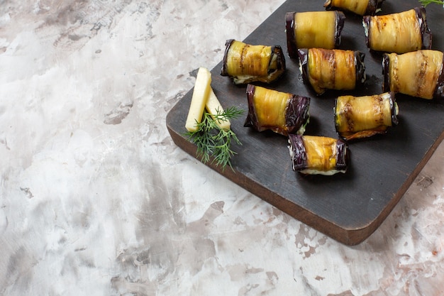 Free photo bottom view grilled eggplant rolls on wood chopping board on abstract background