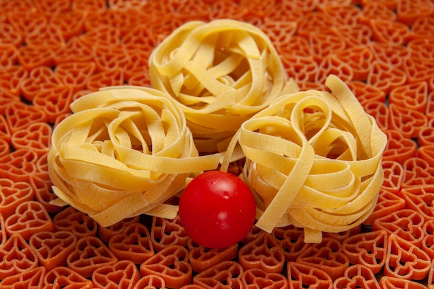 Foto gratuita tagliatelle di pasta italiana a forma di cuore vista dal basso pomodoro ciliegia