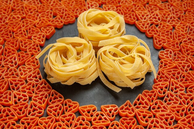 Bottom view heart shaped italian pasta tagliatelles on empty place on dark surface
