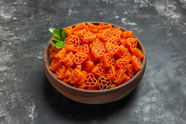 Bottom view heart shaped red italian pasta in a bowl on dark surface