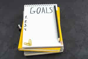 Free photo bottom view list of goals written on notepad pencil sharpener black and yellow pencils gems clips on dark background