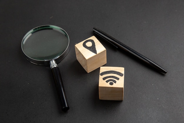 Bottom view location and wifi icons on wood blocks pen lupa on black table