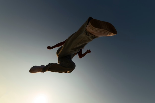 Бесплатное фото Силуэт мужчины, вид снизу, прыгающий на закате
