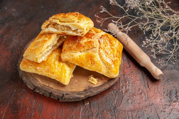 Bottom view penovani khachapuri on wood board rolling-pin on dark red table