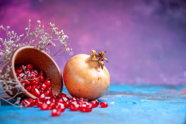 Free photo bottom view pomegranate seeds in wooden bowl a pomegranate on purple free place