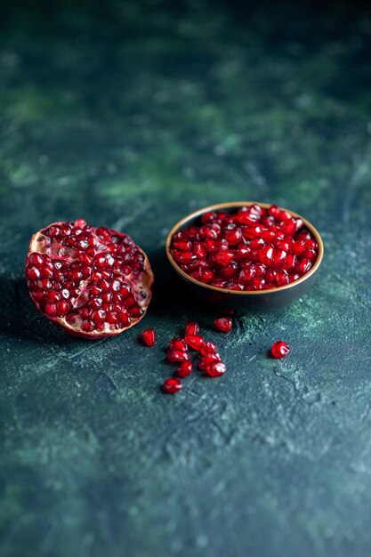 Bottom view pomegrante seeds in small bowl half pomegranate on dark free space