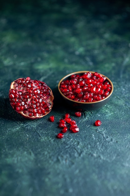 Bottom view pomegrante seeds in small bowl half pomegranate on dark free space