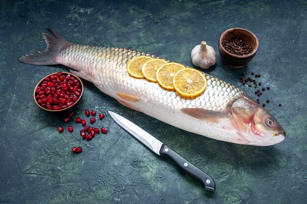 Вид снизу сырая рыба черный перец гранат семена в мисках чесночный нож на столе