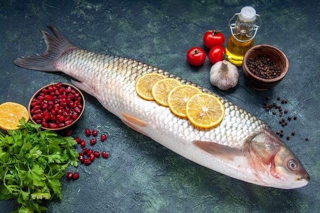 Bottom view raw fish tomatoes lemon slices oil bottle black pepper on table