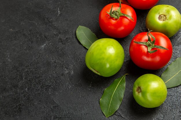 어두운 배경에 하단보기 빨강 및 녹색 토마토와 베이 잎