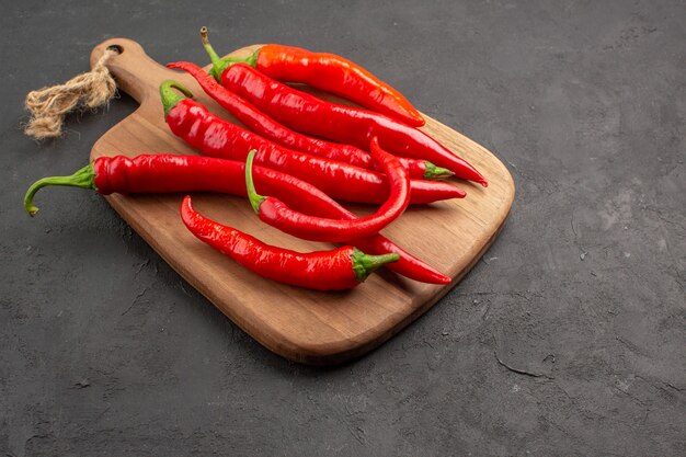 Bottom view red hot peppers on a diagonal chopping board on the black table