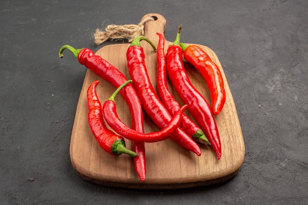 Bottom view red hot peppers on a vertical chopping board on the black table