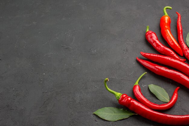 Bottom view red peppers and pay leaves on right side of black table