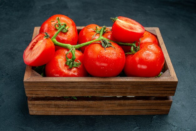 아래쪽 보기 빨간 토마토는 검은색 테이블에 있는 나무 상자에 토마토를 자른다