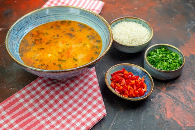 Zuppa di riso vista dal basso in ciotola su tovaglia a quadretti bianca rossa altre cose in ciotole sul tavolo