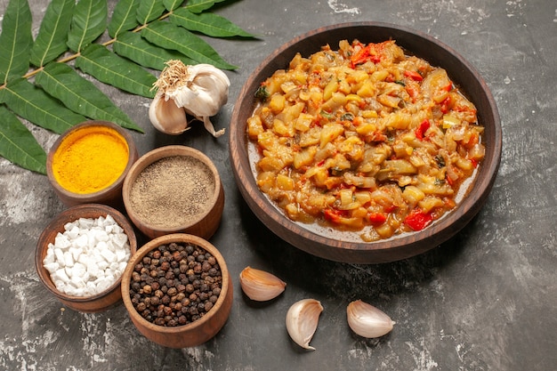 Foto gratuita vista dal basso insalata di melanzane arrostite in una ciotola aglio spezie diverse in piccole ciotole sul tavolo scuro