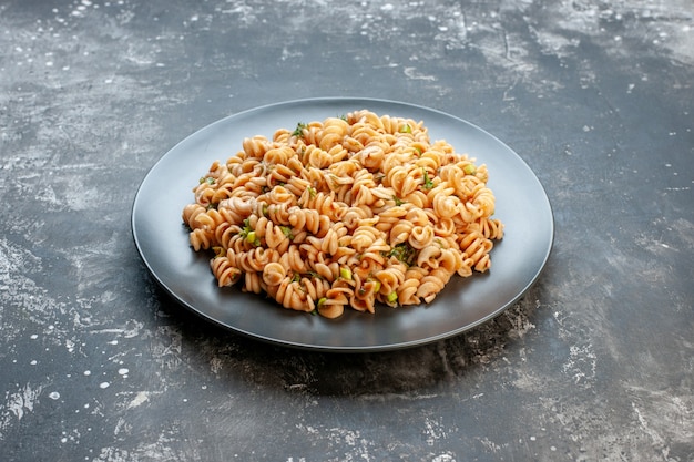 Free photo bottom view rotini pasta on round plate on dark table