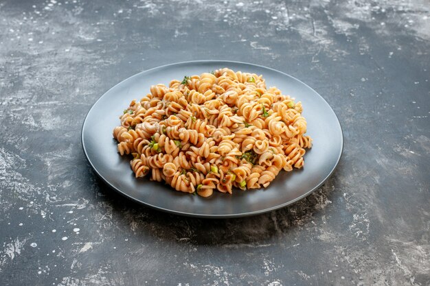 Bottom view rotini pasta on round plate on dark table