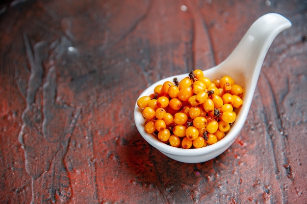 Free photo bottom view sea buckthorn in white bowl on dark red surface copy space