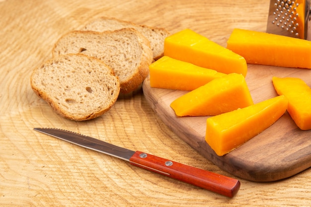 Вид снизу ломтики терки для сыра на разделочной доске, нож, ломтики хлеба на земле