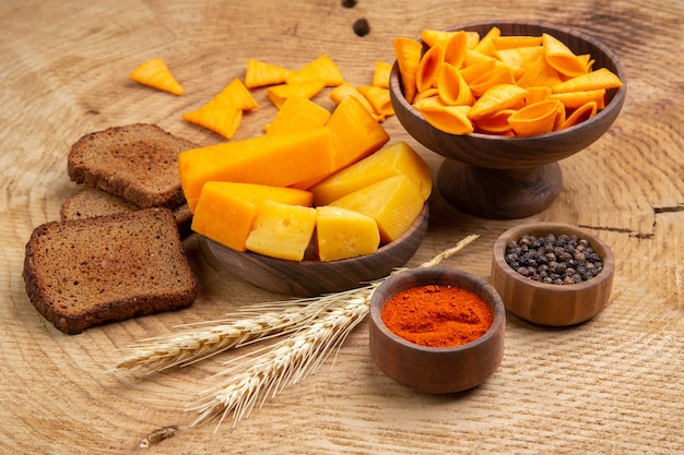 底面図パン小麦スパイクチップのチーズスライスのスライス黒胡椒赤胡椒粉木製テーブルの上の小さなボウルに