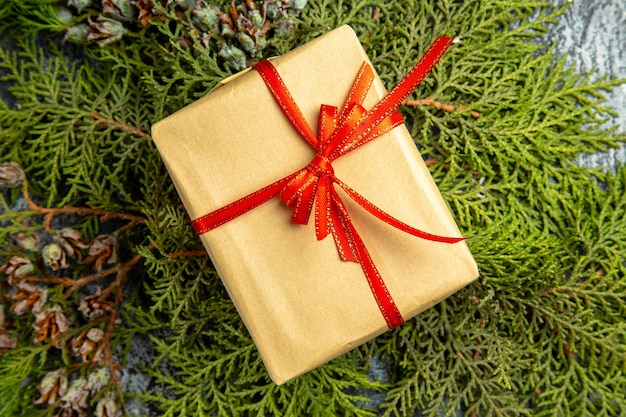 Bottom view small gift tied with red ribbon on pine branches