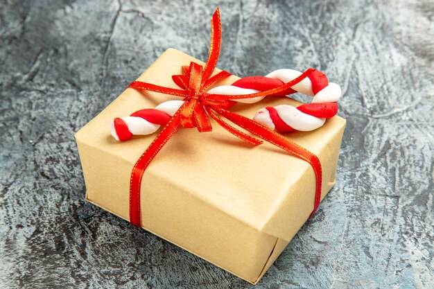灰色の背景に赤いリボンのクリスマスキャンディーで結ばれた底面図の小さな贈り物