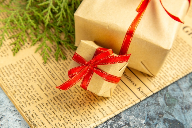 Bottom view small gifts tied with red ribbon on newspaper on dark background