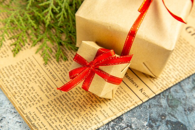 Bottom view small gifts tied with red ribbon on newspaper on dark