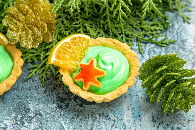 Bottom view small tart with green pastry cream pine branches on grey surface