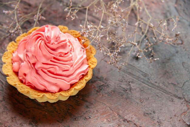 Bottom view small tart with pink pastry cream on dark red table copy space