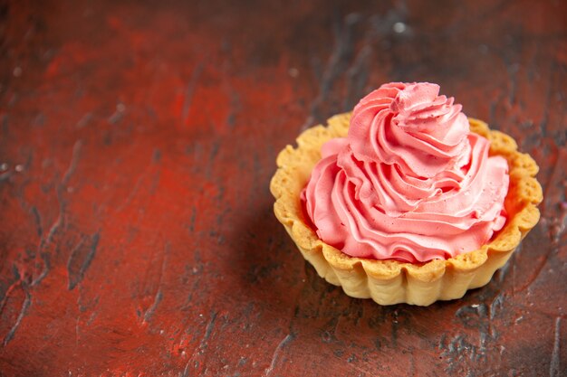 Bottom view small tart with pink pastry cream on dark red table with copy space