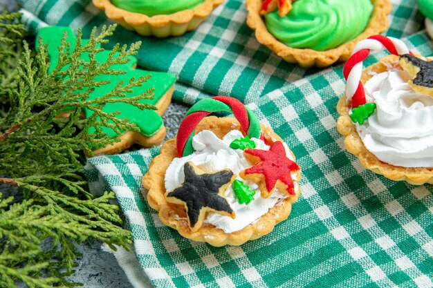 Bottom view small xmas tarts on tablecloth pine branches on grey table