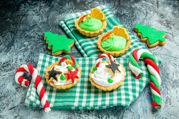 Vista dal basso piccole crostate di natale caramelle di natale su tovaglia a scacchi bianca verde su tavolo grigio