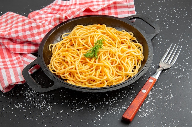 Bottom view spaghetti frying pan fork red and white checkered tablecloth on dark background