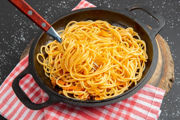 Bottom view spaghetti frying pan on wood board on dark background