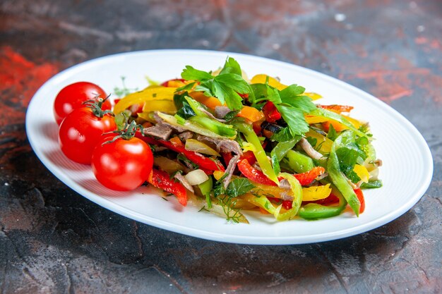 Bottom view vegetable salad cherry tomatoes on oval plate on dark red isolated surface