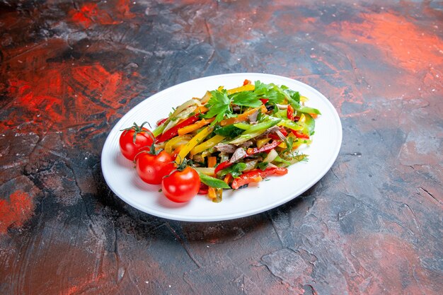 Bottom view vegetable salad on oval plate on dark surface free space