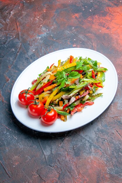 Bottom view vegetable salad on oval plate on dark surface