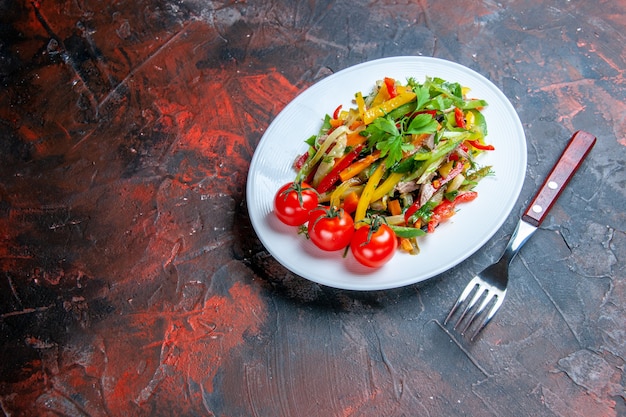 暗い表面の自由な場所の楕円形のプレートフォークの底面図野菜サラダ