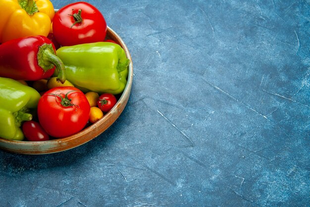 Bottom view vegetables cherry tomatoes different colors bell peppers tomatoes on wooden platter on blue surface free place