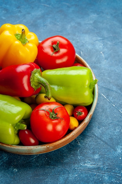 Free photo bottom view vegetables cherry tomatoes different colors bell peppers tomatoes on wooden platter on blue table